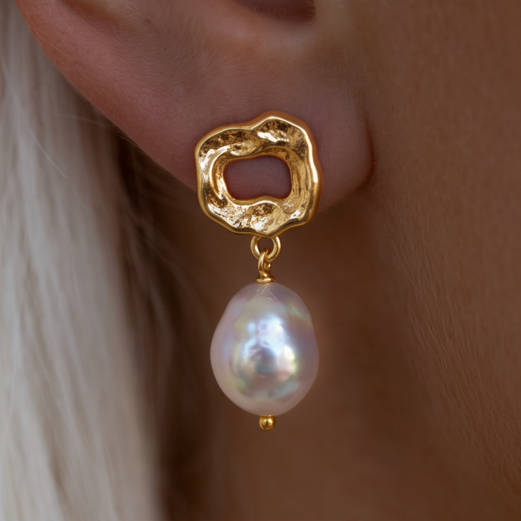 Molten Pearl drop earrings worn on the ear, white pearl hanging from textured gold, light hair