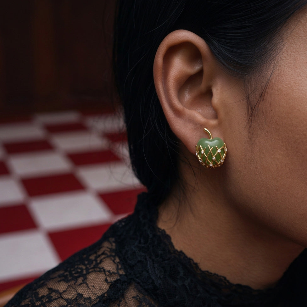 Granny Smith Apple stud earrings worn on the ear, green apple in a gold lattice with a black lace top behind