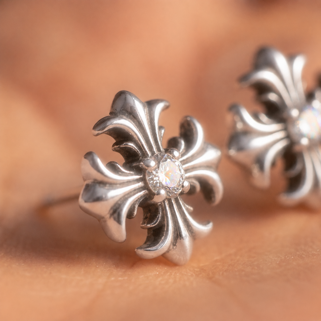 Fleur Cross crystal stud earrings close-up in a hand, two silver crosses each with a center crystal