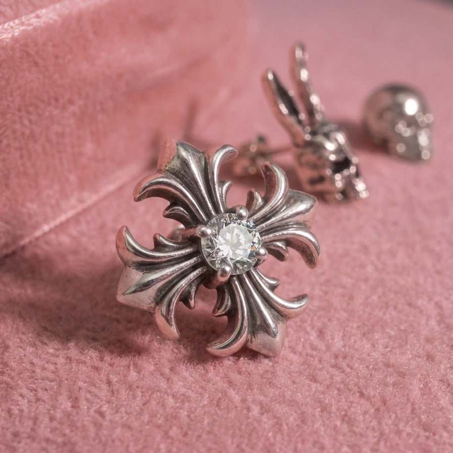 Fleur Cross crystal stud earrings on pink velvet, silver cross with a center crystal, other jewelry blurred behind