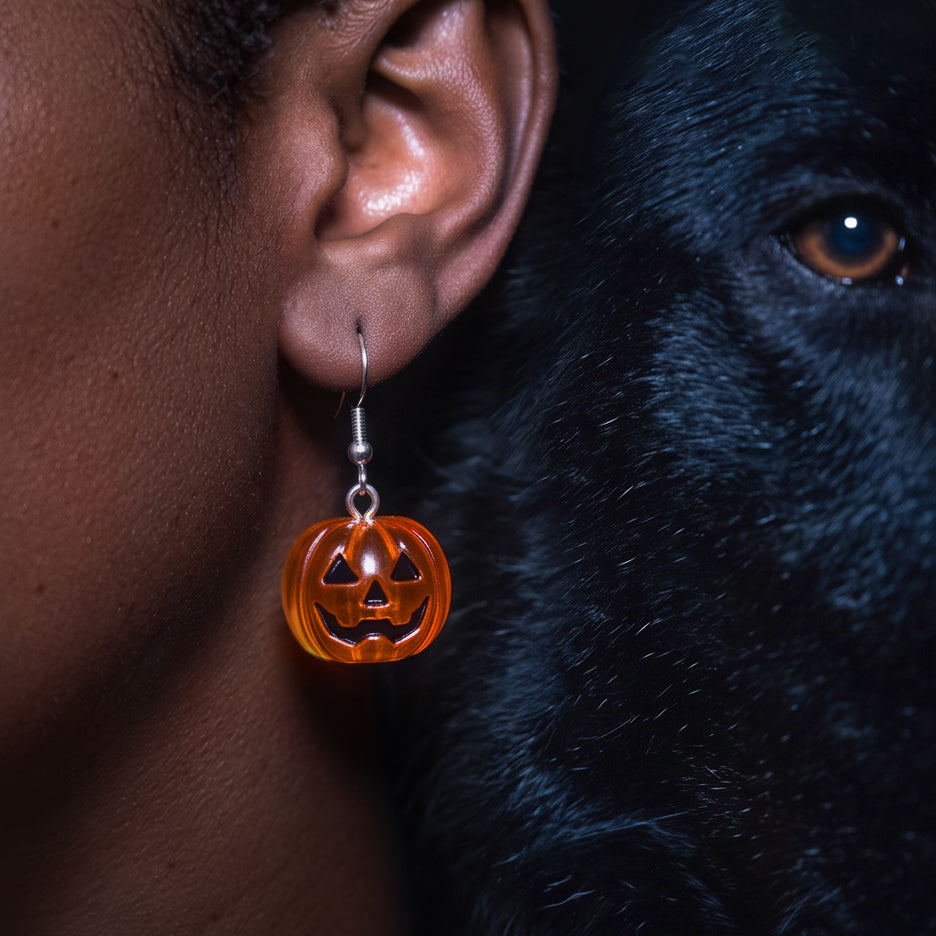 Candy Pumpkin drop earring worn on the ear, orange jack-o-lantern pumpkin beside a black dog's face