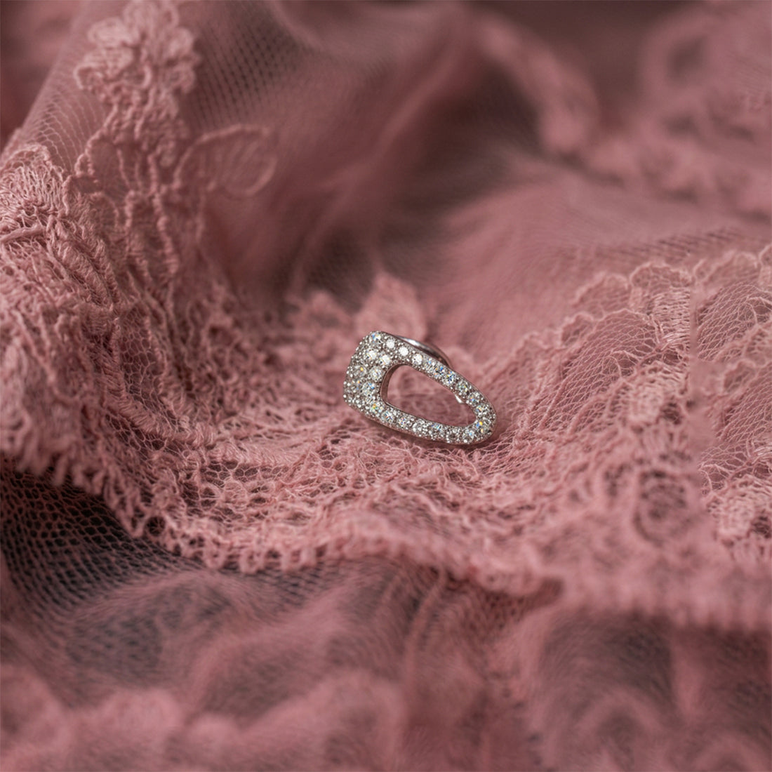 Crystal Hair-Clip ear cuff laid flat on dusty pink lace, an open crystal-covered silver shape