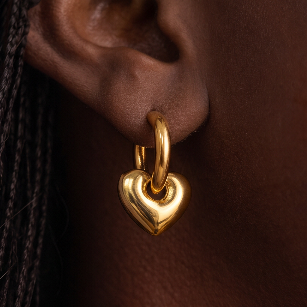 Chunky Heart Hoop earring worn on the ear, close-up of the gold hoop and heart drop