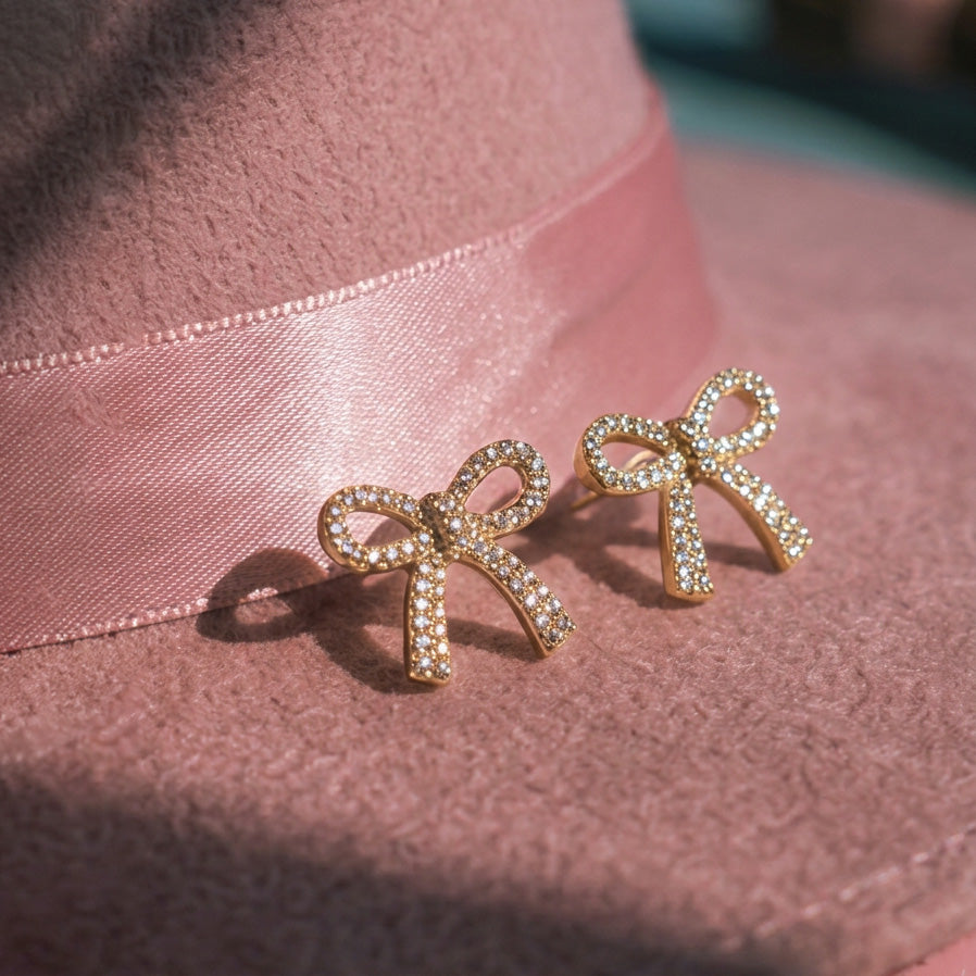 Crystal Bow stud earrings pair on a pink felt hat with a pink satin band, crystal-set gold bows