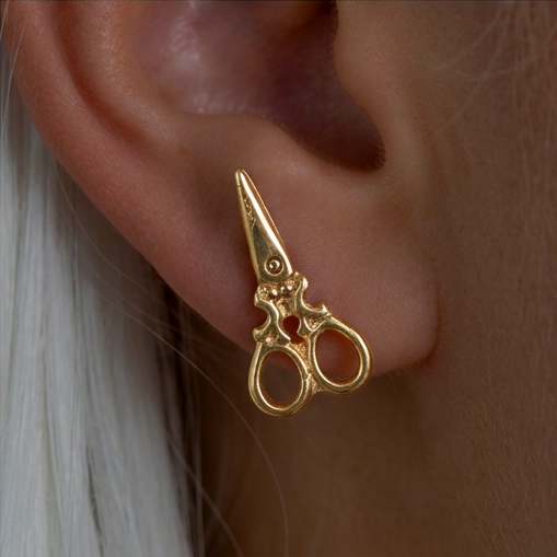 Scissors stud earrings, a gold scissors-shaped stud worn on the ear with white hair behind