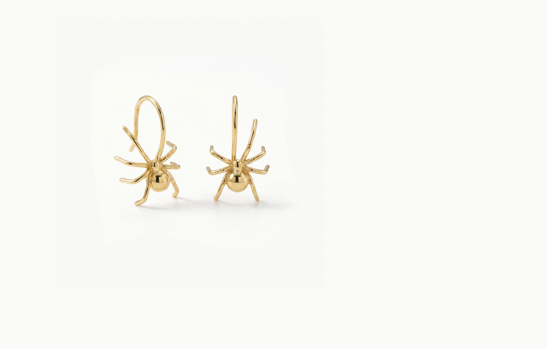 Gold spider earrings hanging by one long leg