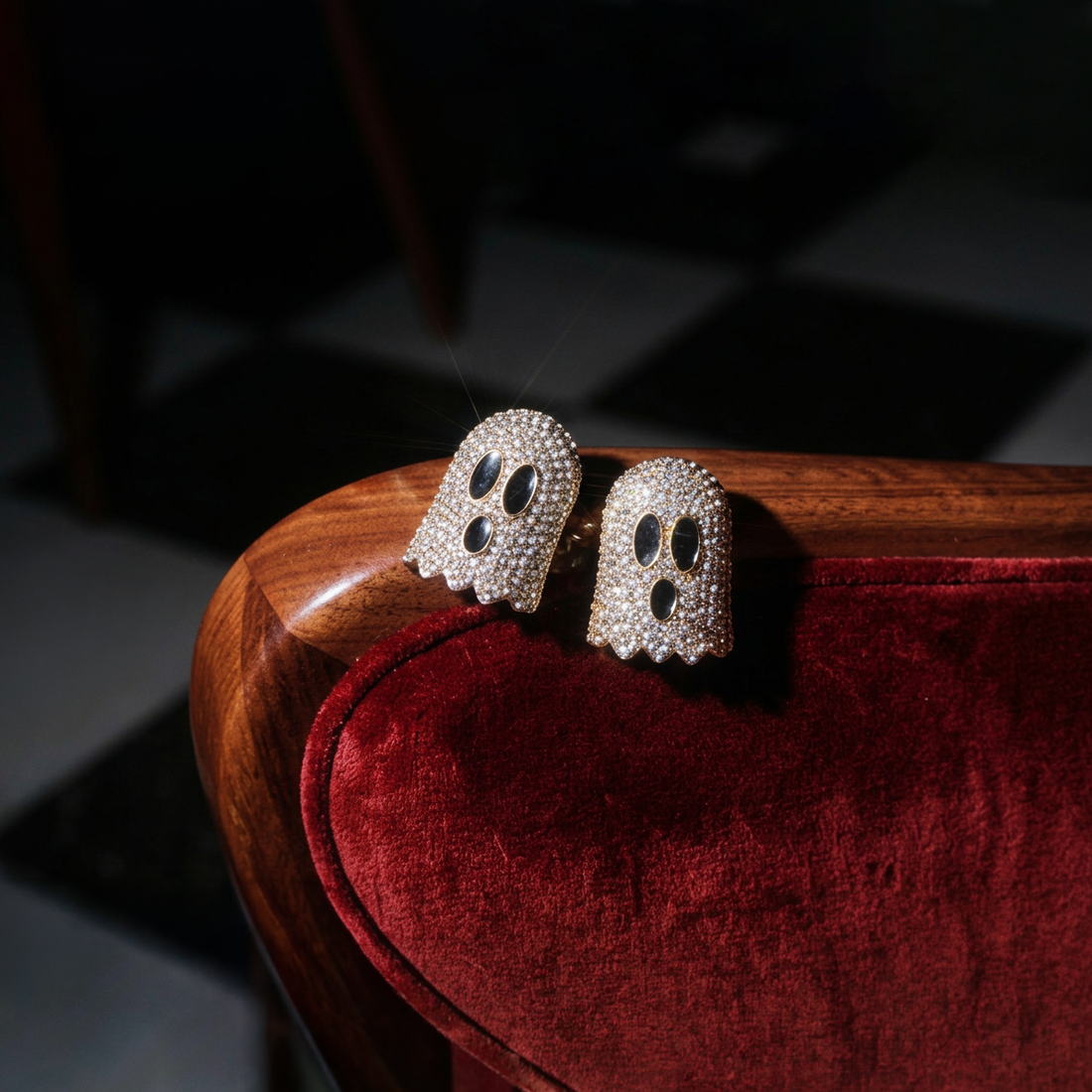 Crystal Boo earrings, two ghosts covered in sparkling crystals resting on a red velvet chair arm
