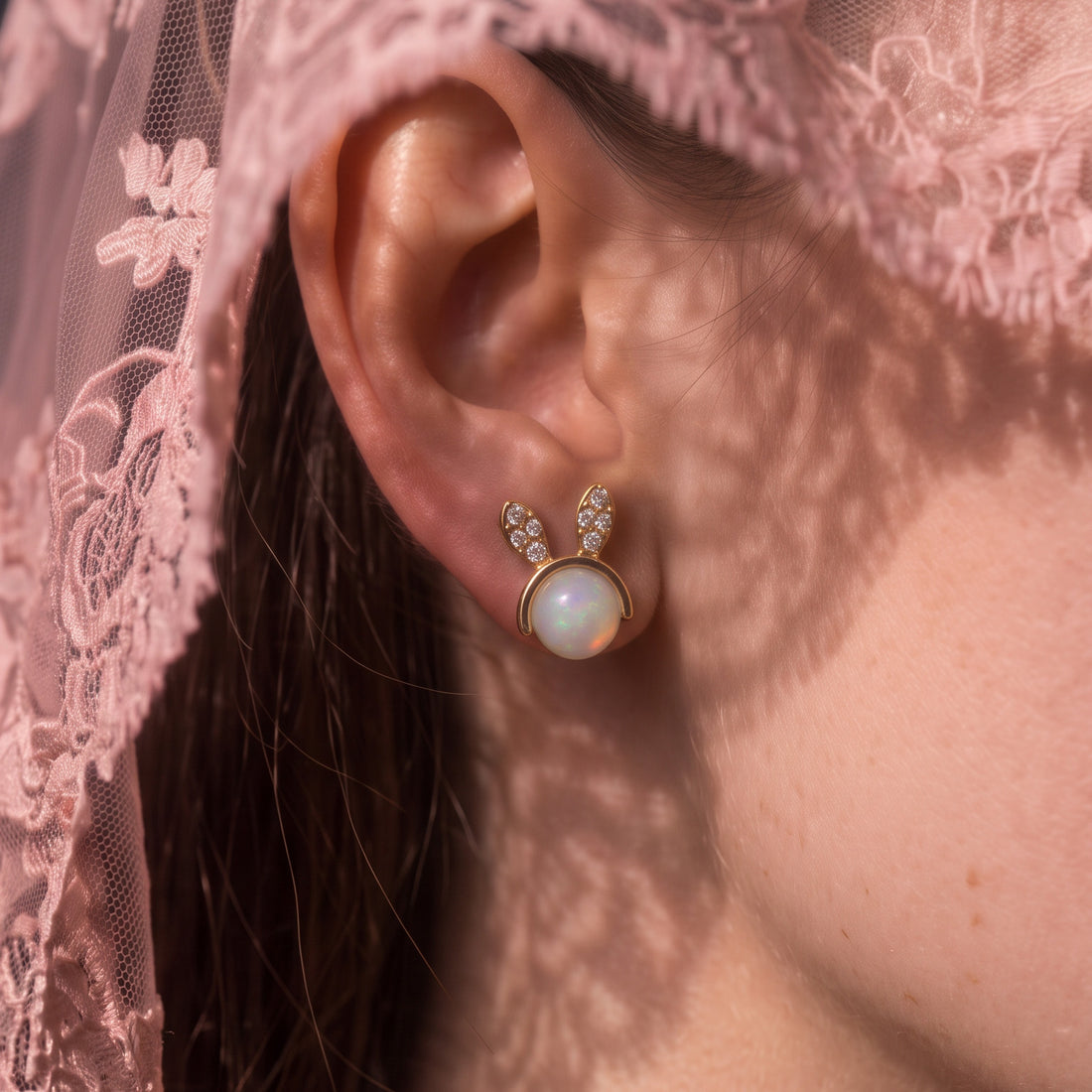 Mini Bunny stud earrings worn on the ear, gold bunny ears with a round white bead, pink lace behind