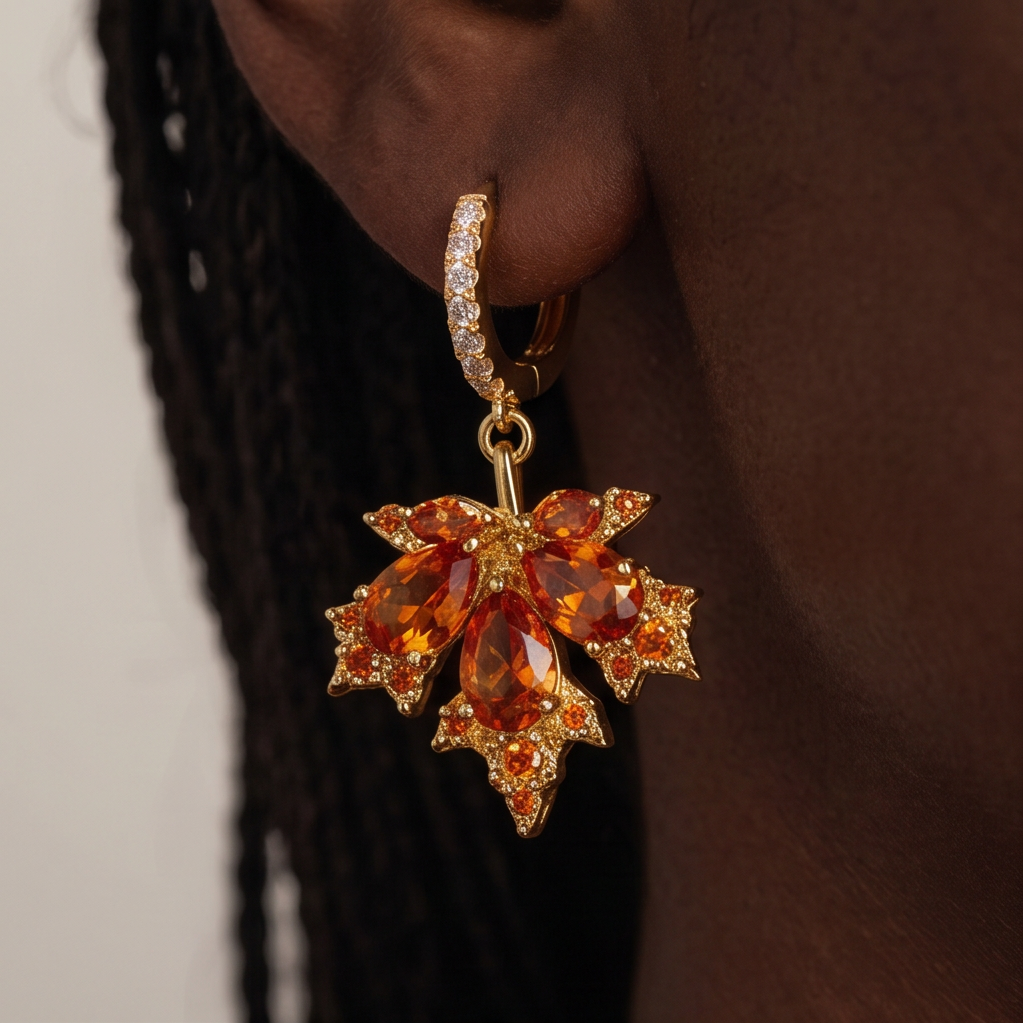Maple Leaf crystal drop earrings worn on the ear, orange crystal leaf hanging from a gold huggie, braided hair