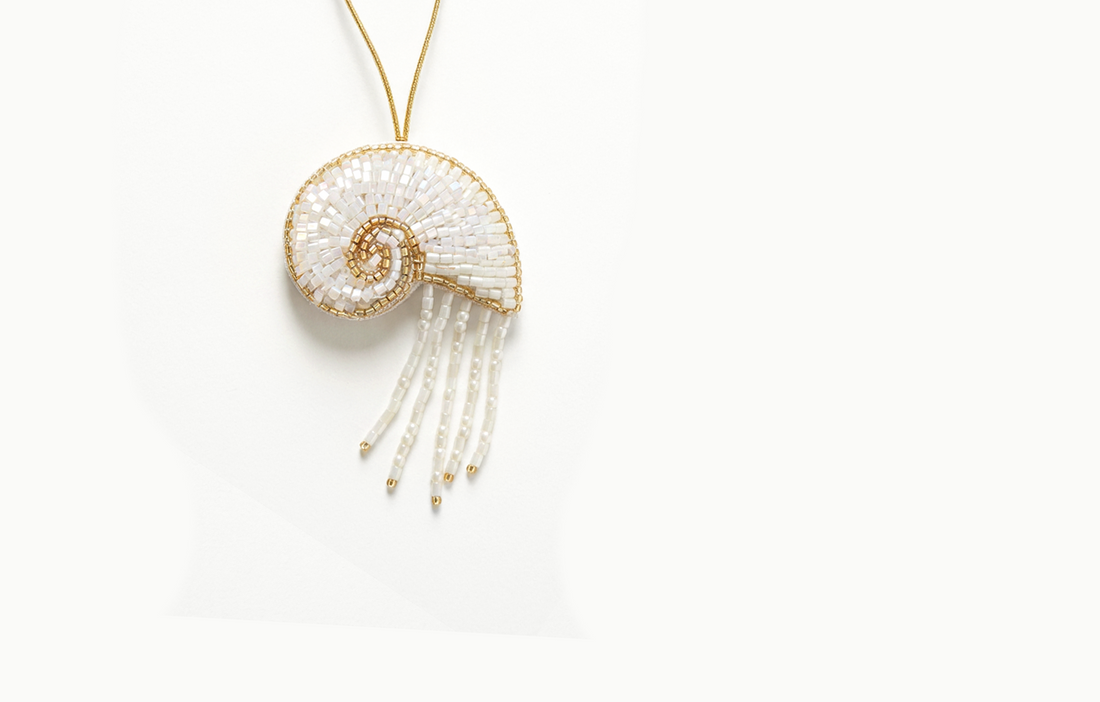 White and gold beaded spiral shell bag charm with bead fringe