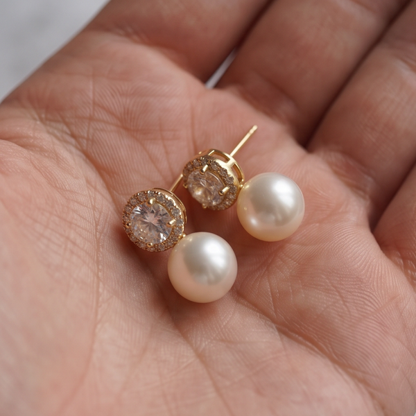 Halo Crystal Pearl earrings resting in an open palm, white pearls under gold crystal halos