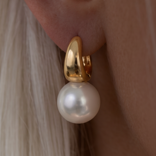 Classic Pearl drop earrings, close-up of a white pearl hanging from a gold curved top on the ear