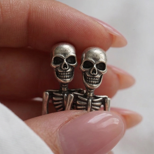 Hanging Skeleton earrings, two silver skeletons with grinning skulls held between fingertips