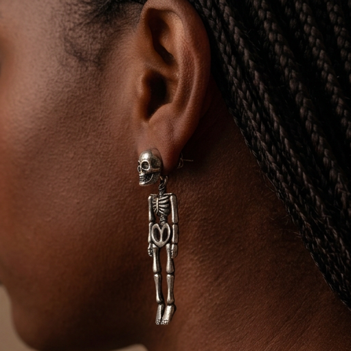 Hanging Skeleton earrings worn on the ear, a silver skull stud with a skeleton dangling below, side view