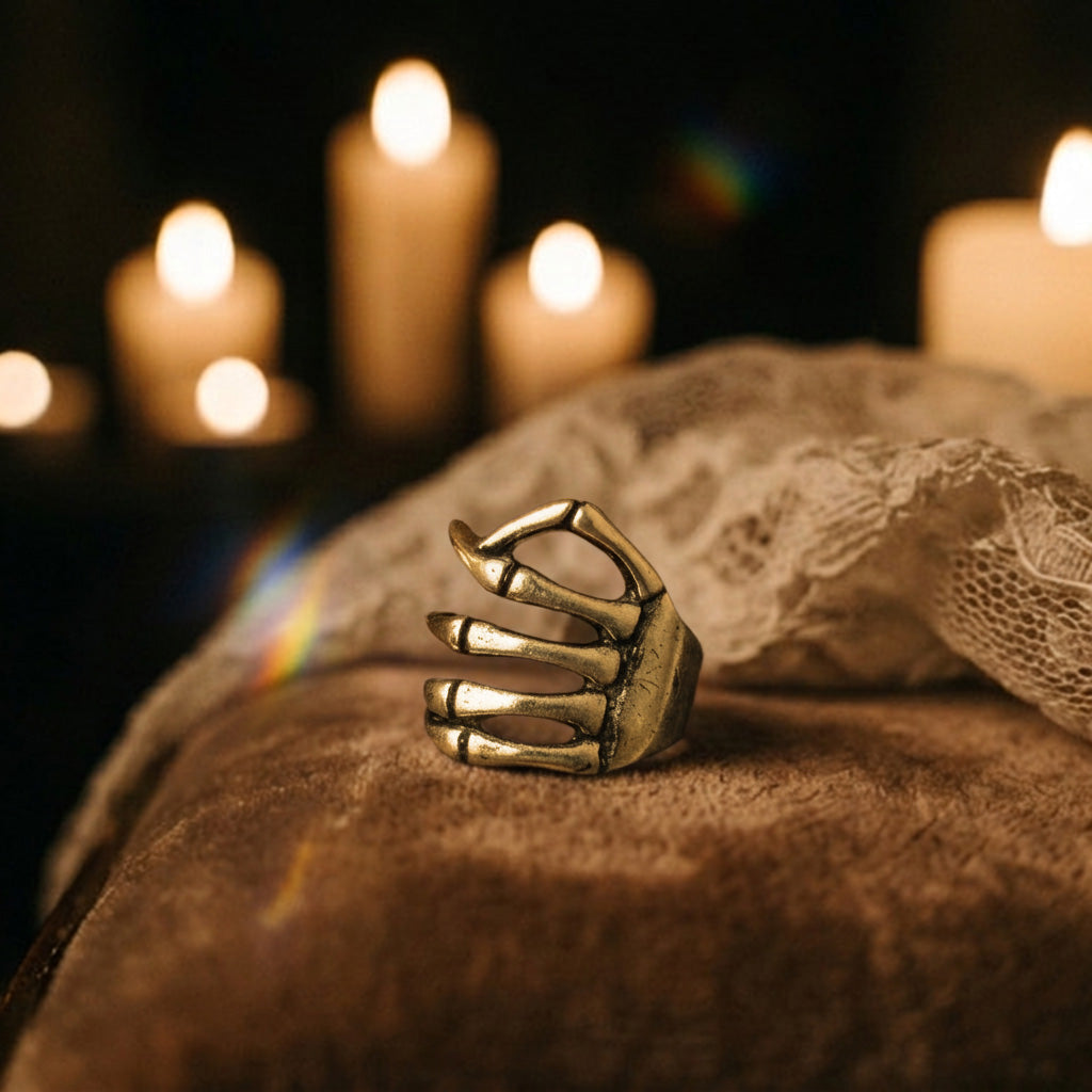 Golden Skeleton Hand ear cuff resting on a lace-draped dark surface with lit candles behind