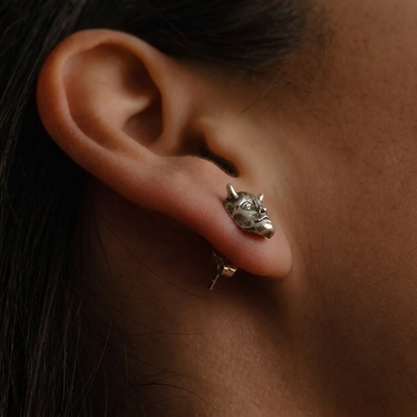 Jekyll & Hyde stud earrings, a silver horned face worn on the ear, side view with the post visible