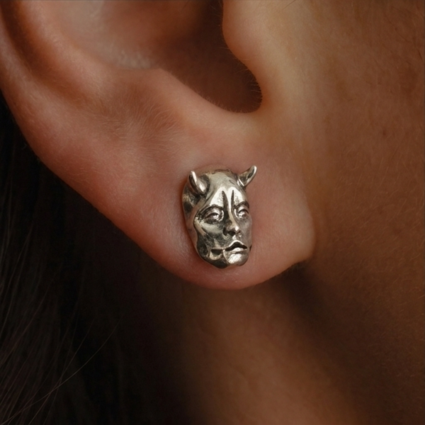 Jekyll & Hyde stud earrings, close-up of a silver horned face worn on the ear