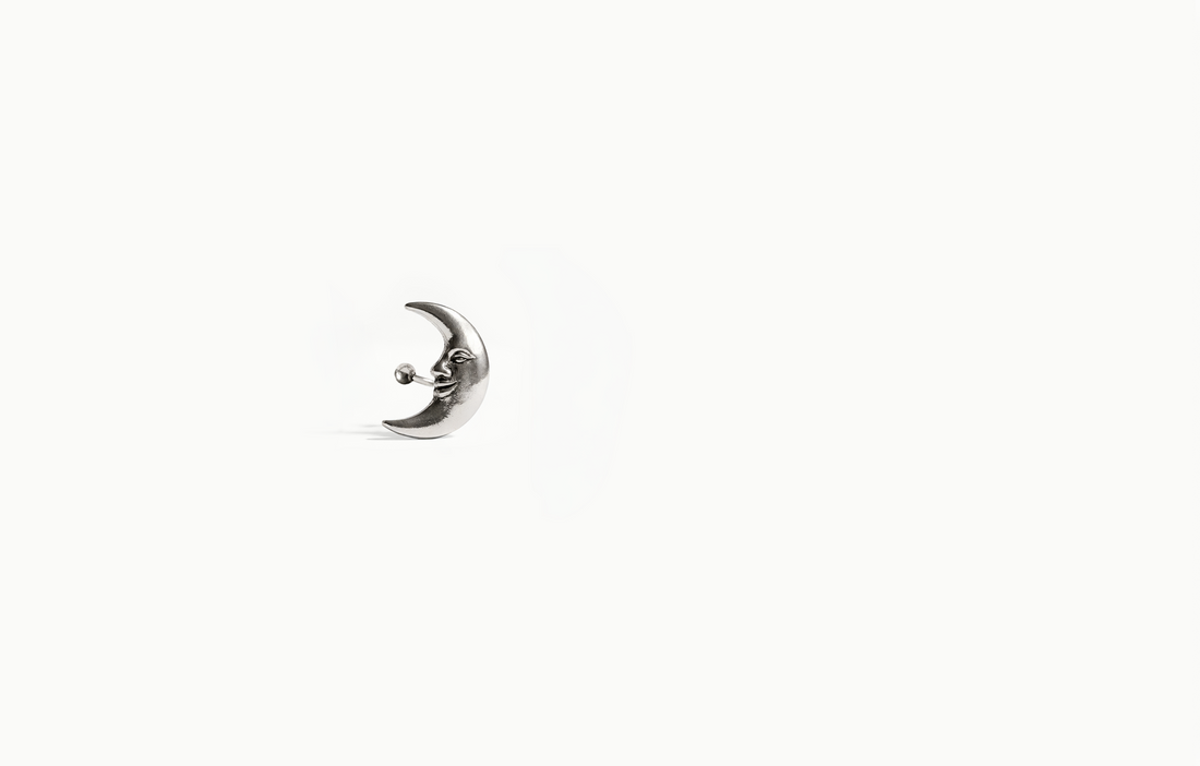 Silver crescent moon earring with a face