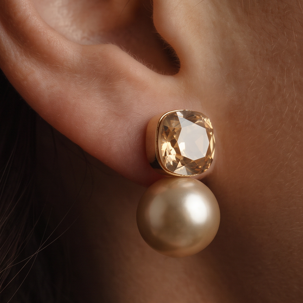 Toffee crystal pearl earrings worn on the ear, a square amber crystal stud above a cream pearl