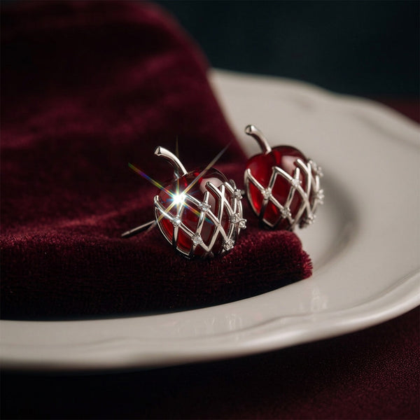 Bravo Apple stud earrings pair on a red velvet cloth and white plate, red apples in a silver lattice