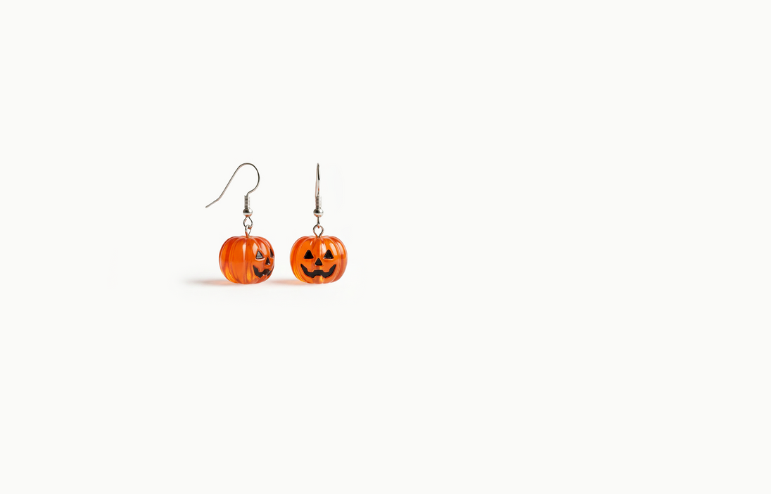 Translucent orange pumpkin drop earrings with a jack-o'-lantern face