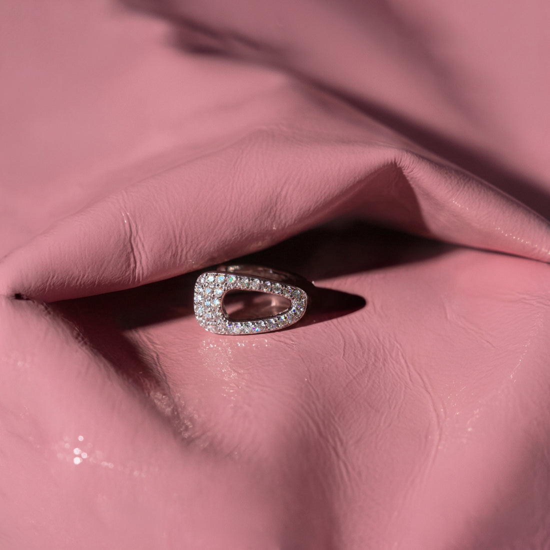 Crystal Hair-Clip ear cuff on pink glossy fabric, an open crystal-covered silver shape in soft light