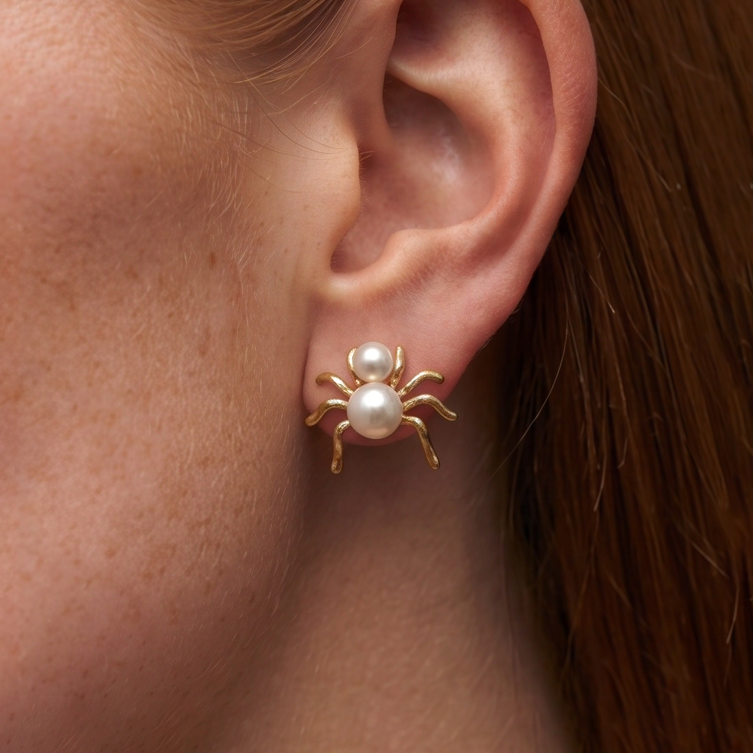 Pearl Spider stud earrings worn on the ear, wider view with auburn hair in the background