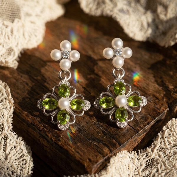Victorian Crystal Drop earrings pair on rough wood with cream lace, pearls above green jewel flowers