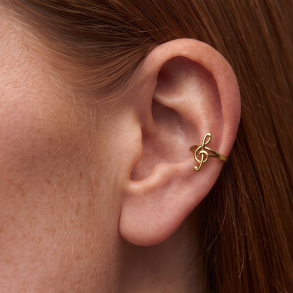 Treble Ear Cuff worn on the ear, small gold treble clef shape, with auburn hair behind