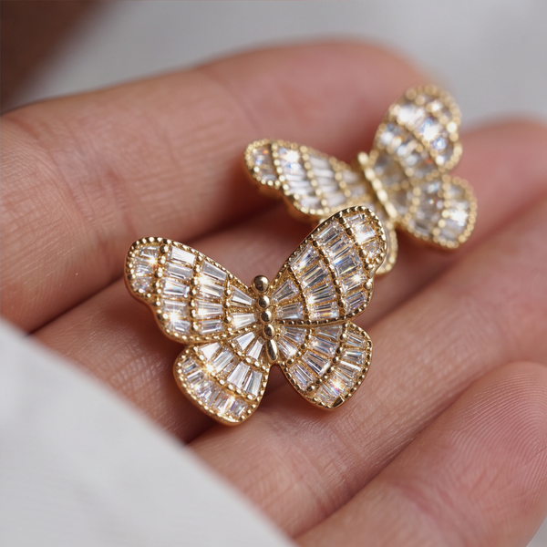 Heirloom Crystal Butterfly earrings held on a hand, gold butterflies set with rectangular crystals