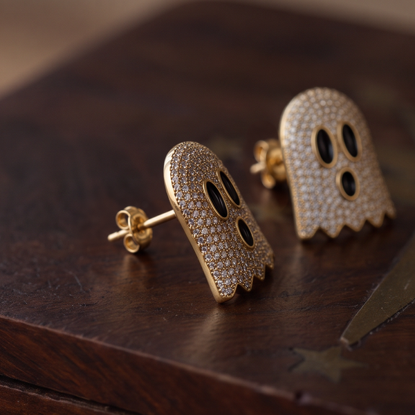 Crystal Boo earrings, two gold ghosts covered in crystals with black eyes on a dark wooden surface