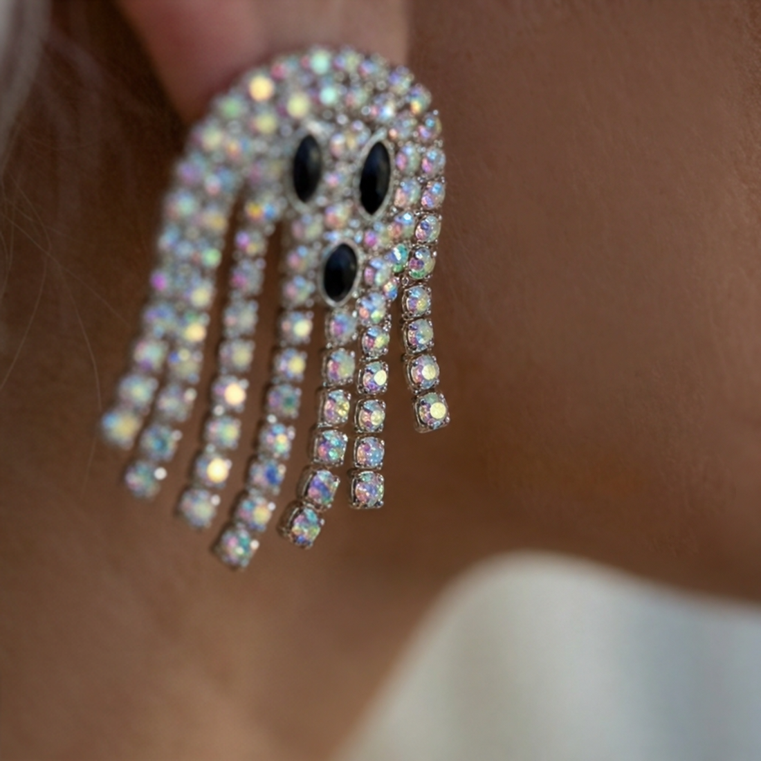 Disco Ghost Crystal earrings close-up, a ghost with black eyes and strands of iridescent crystals
