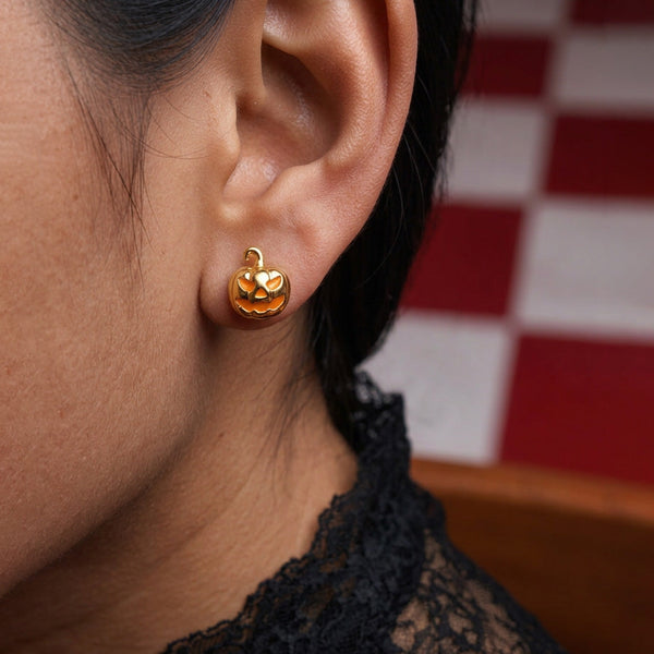 Golden Jack Pumpkin stud earrings worn on the ear, a gold jack-o'-lantern with orange face, black lace collar