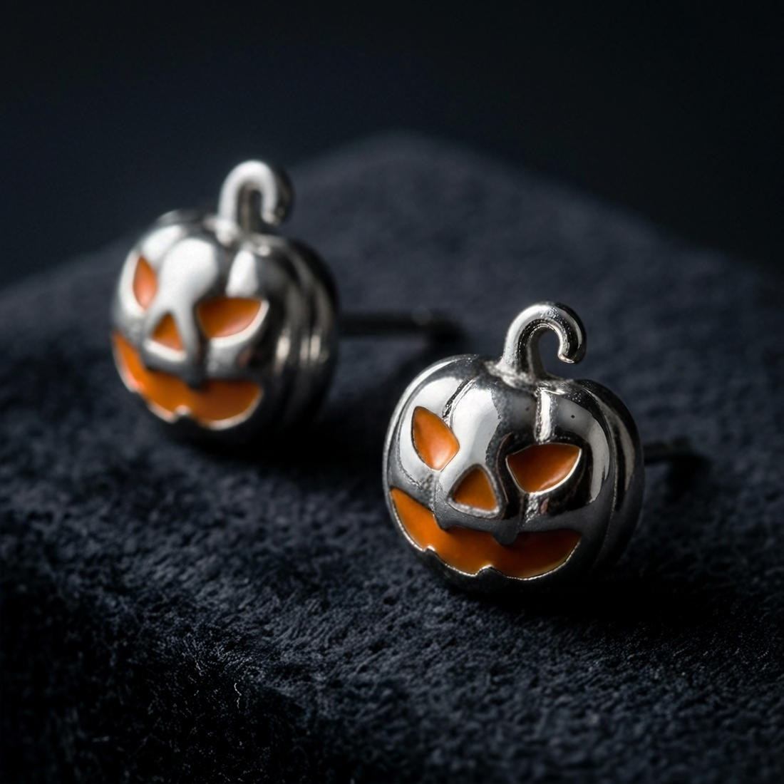 Silver Jack Pumpkin stud earrings, two silver pumpkins with orange faces on black fabric