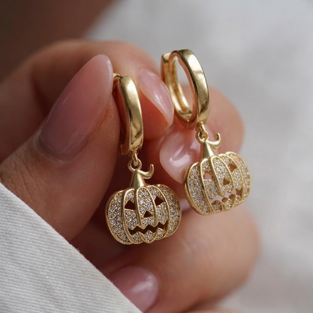 Pumpkin Spice crystal drop earrings, gold huggie hoops with crystal pumpkins held in a hand