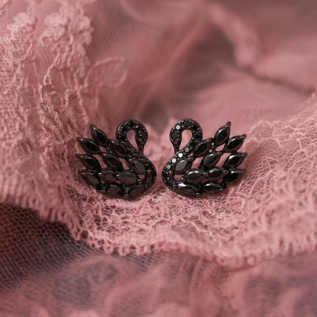 Black Swan earrings, a pair of black crystal swans laid flat on dusty pink lace