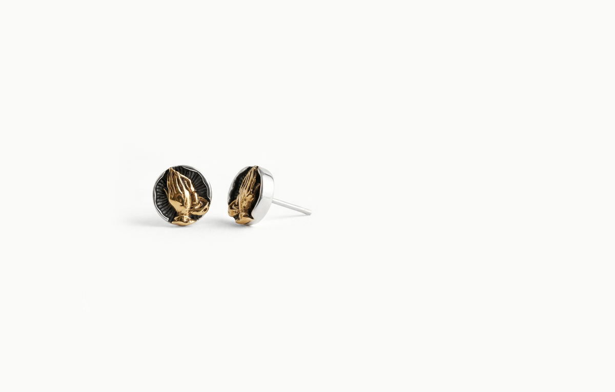 Round silver stud earrings with gold praying hands