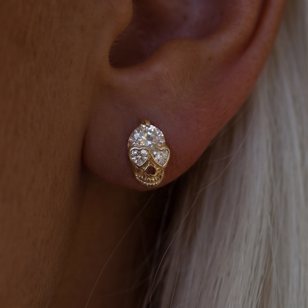Crystal Skull stud earrings, close-up on the ear with white hair, heart-shaped crystal eyes and a round crystal