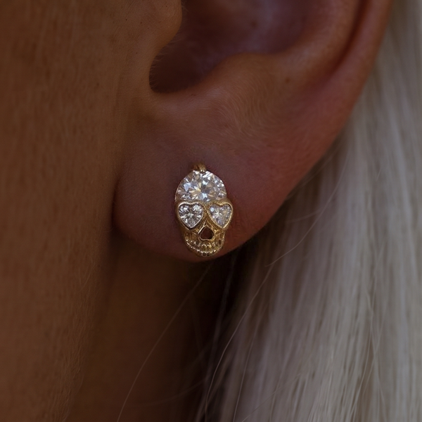 Crystal Skull stud earrings, close-up on the ear with white hair, heart-shaped crystal eyes and a round crystal