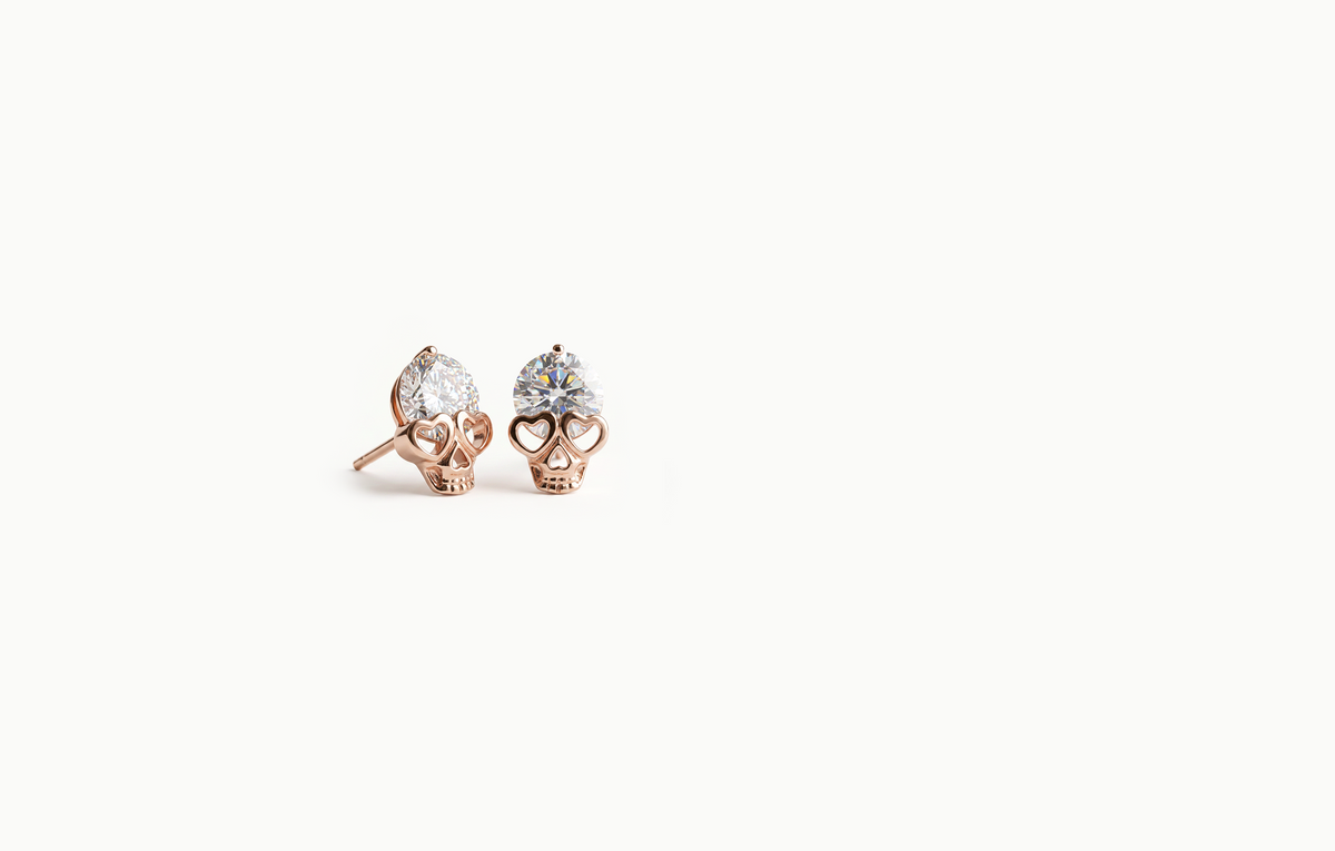 Rose gold skull stud earrings with heart eyes and a large crystal