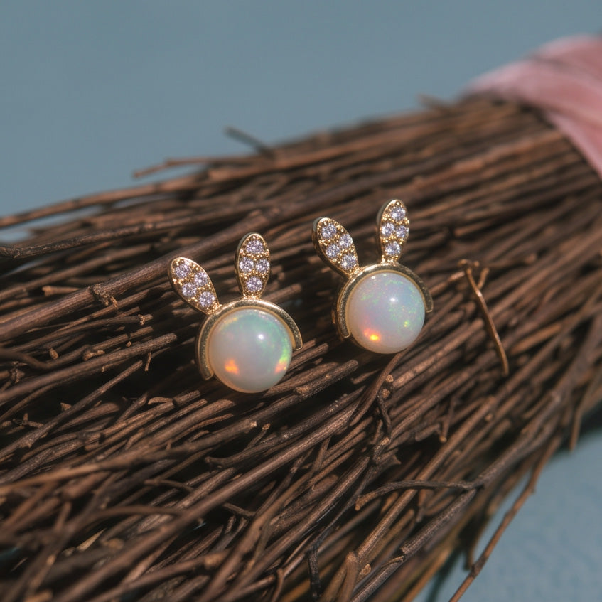 Mini Bunny stud earrings, a pair resting on a bundle of dry brown twigs