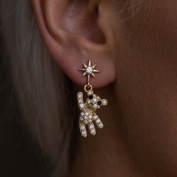 Teddy Bear crystal drop earrings, close-up of a gold crystal bear dangling from a star stud on the ear