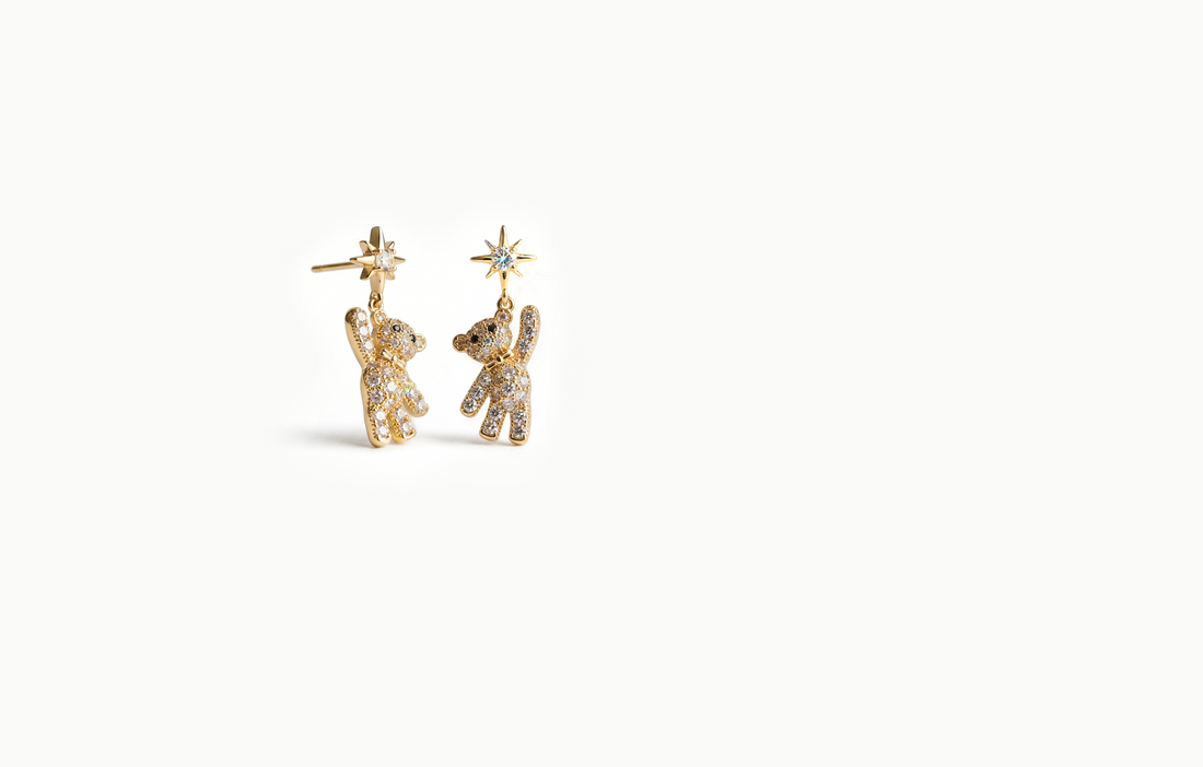 Gold drop earrings with a crystal teddy bear hanging from a starburst stud