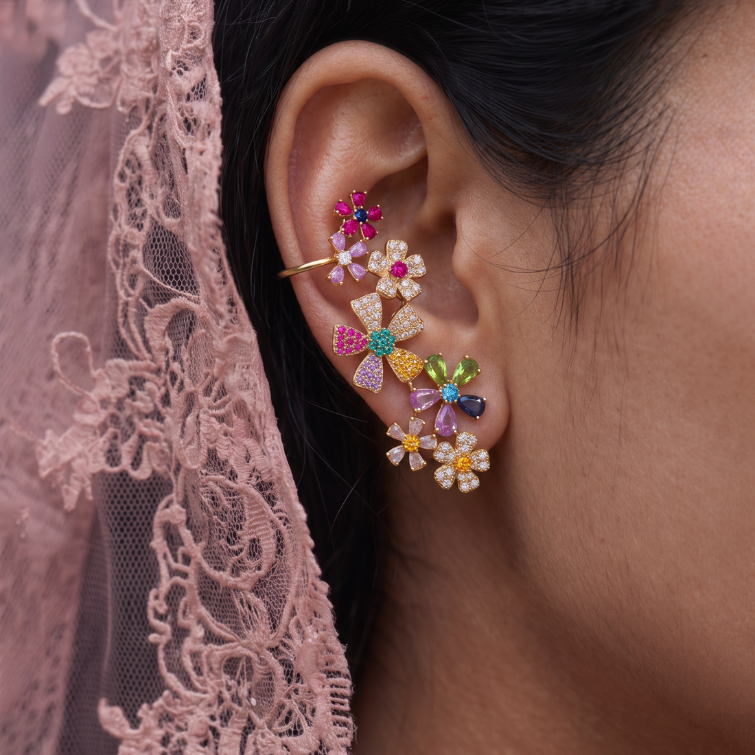 Meadow Valley crystal earrings worn on the ear against a pink lace veil, multicolor flowers