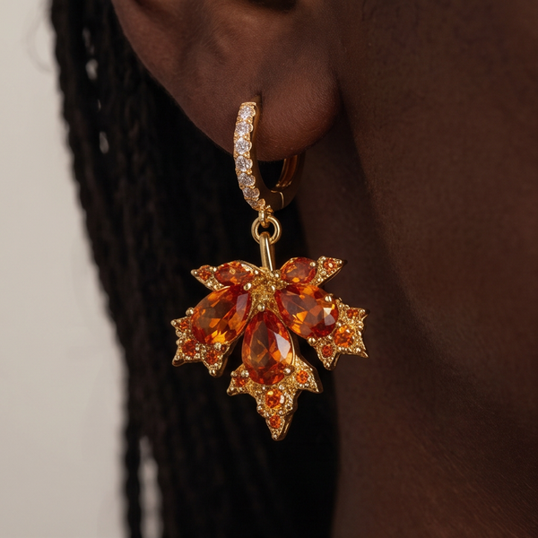 Maple Leaf crystal drop earrings worn on the ear, orange crystal leaf hanging from a gold huggie, braided hair